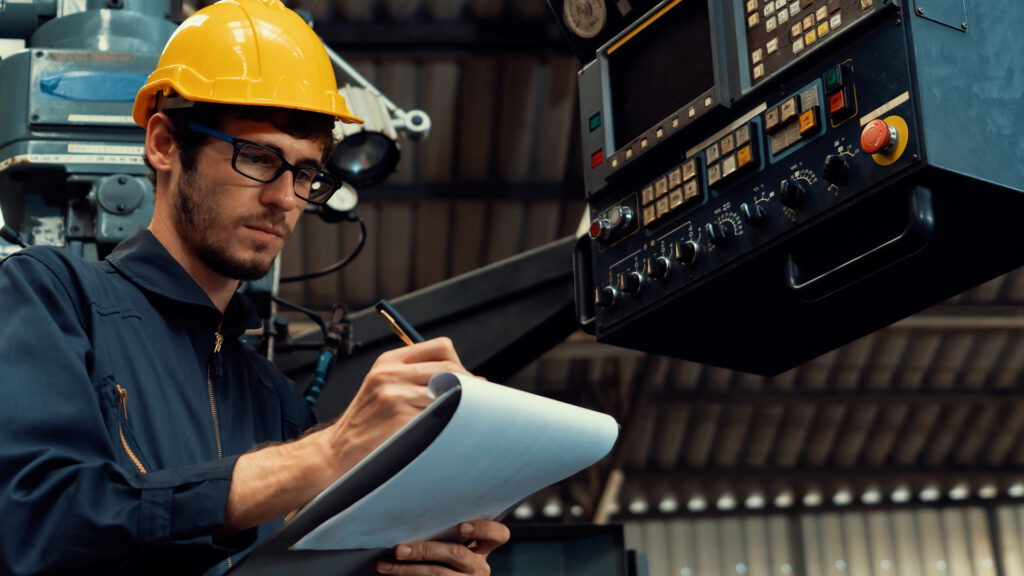 a man wearing a hard hat and glasses working on a machine