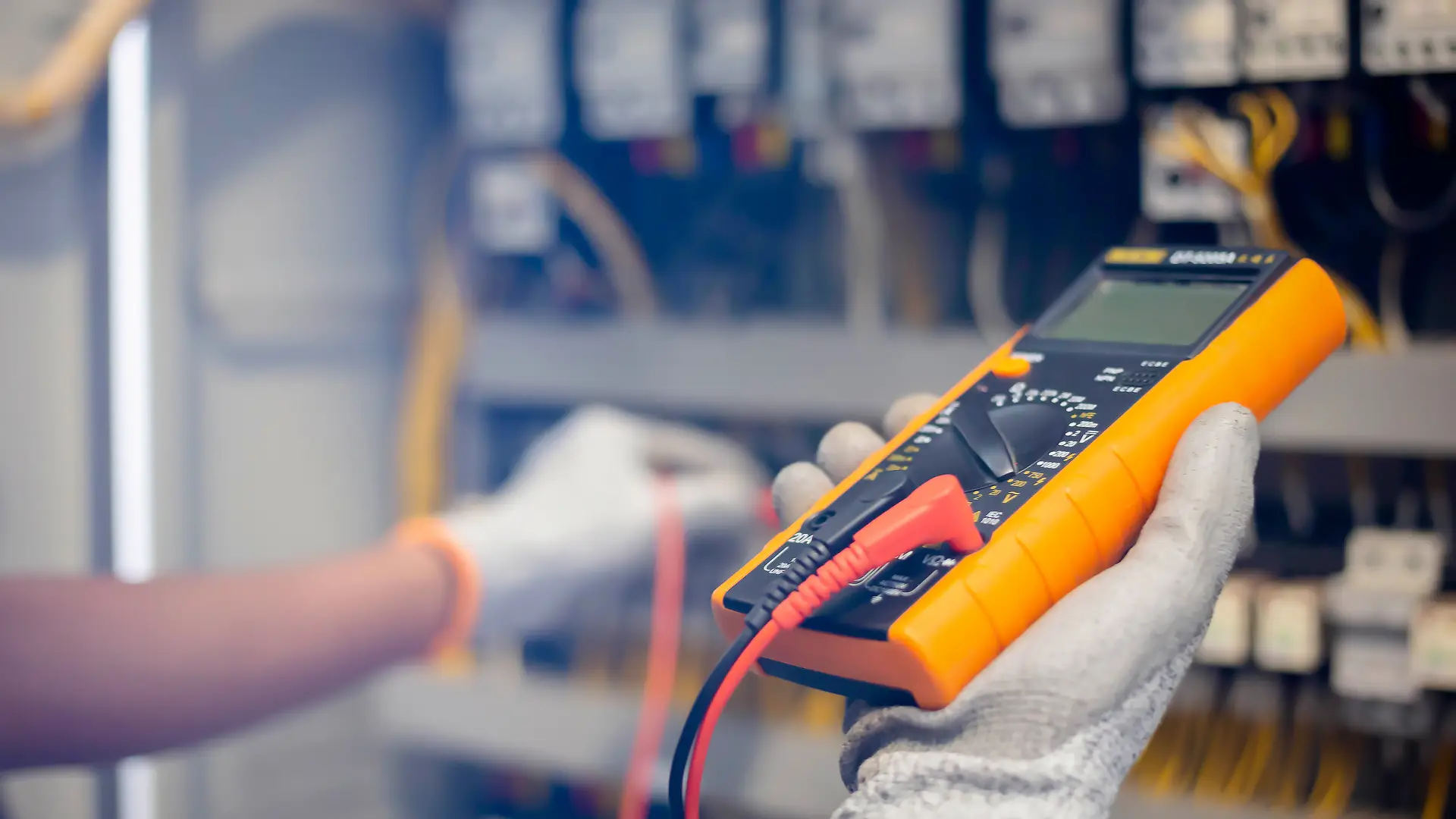 Electrician engineer uses a multimeter to test the electrical installation and power line current in an electrical system control cabinet. Multimeter Calibration.